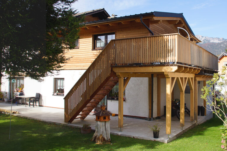 Foto einer Außentreppe aus Holz die auf eine Holzterrasse führt.