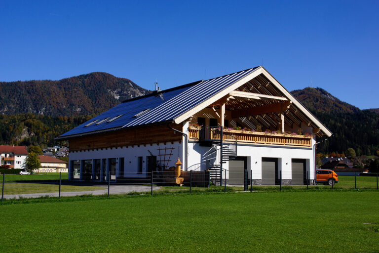 Foto eines Gebäudes in Holzriegelbauweise. Das Giebeldach is mit Photovoltaik-Panelen belegt.