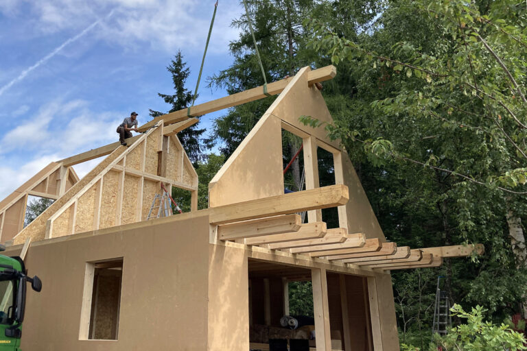 Montage eines Fertigteilhauses in Holzriegelbauweise. Firtsparren wird eingesetzt.